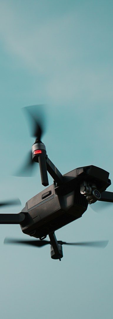 Schwarzer Drohne fliegt vor blauem Himmel mit einigen Wolken.